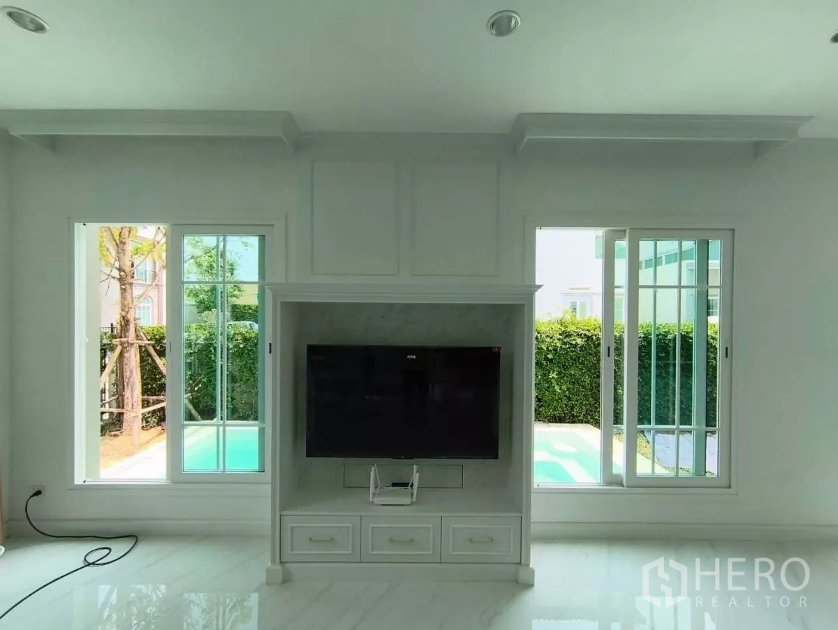 Detached House for rent in Bang Phli, Samut Prakan - Built-in TV wall between two large windows with views to the private pool and hedged garden.