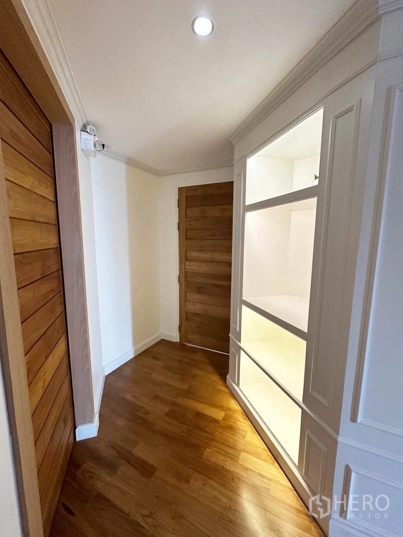 Condominium for sale in Khlong San, Bangkok - Hallway with illuminated display shelves and wooden doors.