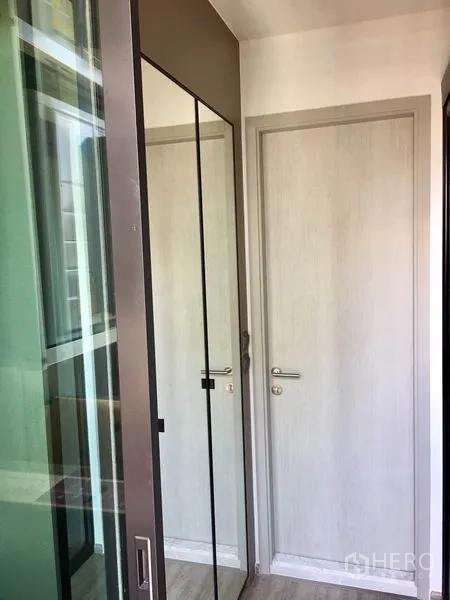 Condominium for rent in Watthana, Bangkok - Entry corridor with light-toned doors and a mirrored closet beside a large window.