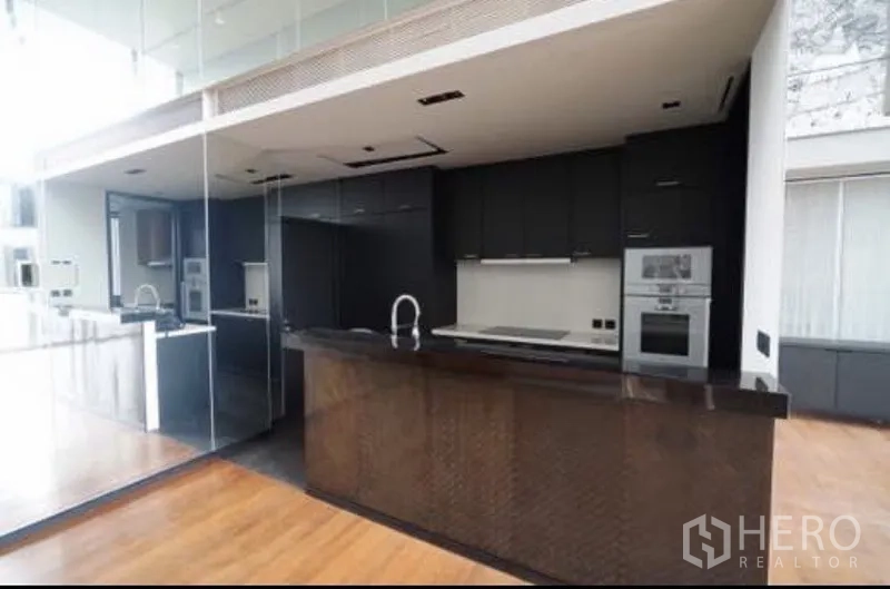 公寓 出租在Sathon, Bangkok - 现代主厨房，黑色橱柜、白色台面、嵌入式烤箱与吧台台面。