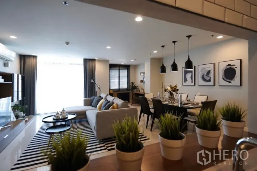 คอนโด ให้เช่าในWatthana, Bangkok - โซนรับแขกและรับประทานอาหารแบบเปิด โซฟาสีเทา พรมลายทาง โคมไฟแขวน และโต๊ะอาหารจัดเต็ม