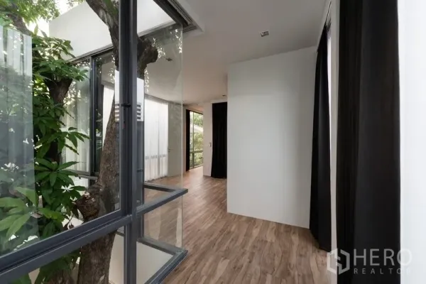 Office Space for rent in Watthana, Bangkok - Glass atrium wrapping an existing tree with warm wood floors and natural light.