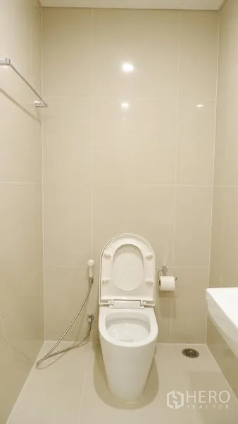 公寓 出租在Watthana, Bangkok - 极简卫生间，坐便器带喷枪，浅色墙面