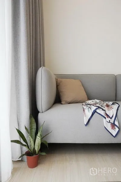 公寓 出租在Pathum Wan, Bangkok - 极简风沙发角，抱枕与披巾，落地窗旁摆放绿植