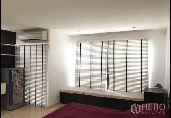 Townhouse for sale in Khlong Toei, Bangkok - Bright bedroom with window blinds, built-in bench seating and wall air conditioner.