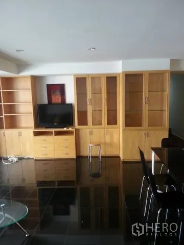 公寓 出租在Bang Rak, Bangkok - 客厅墙面设木质电视柜与展示书柜，储物空间充足。