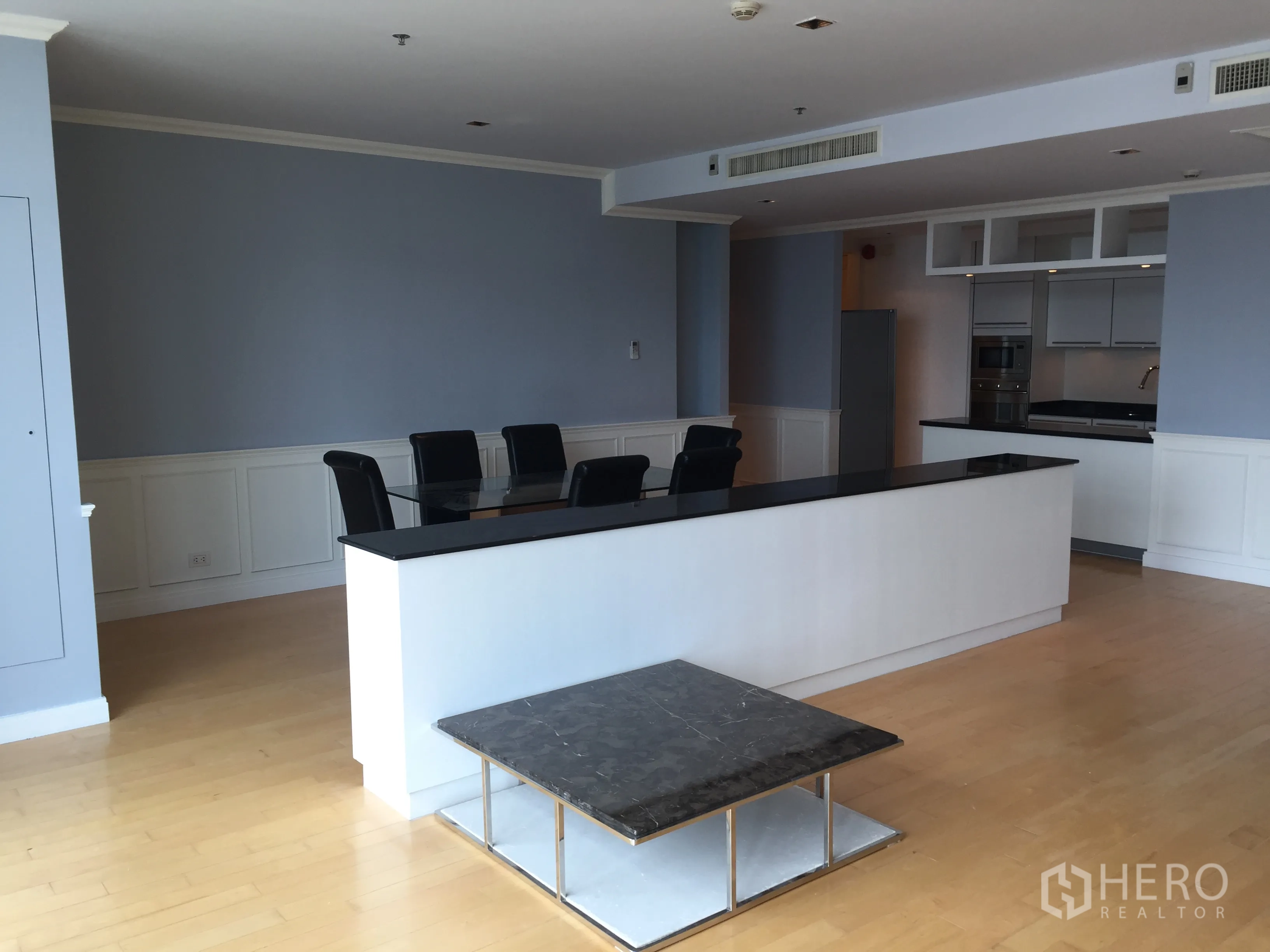 Condominium for rent in Pathum Wan, Bangkok - Open-plan living and dining area with black stone breakfast bar and light wood floors.