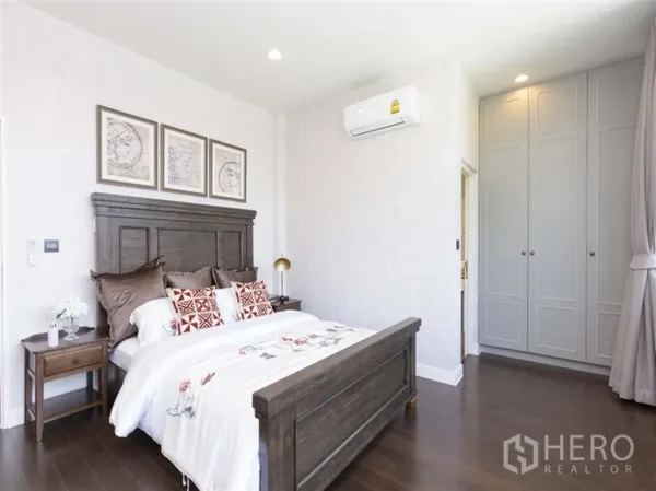 Detached House for rent in Bang Kapi, Bangkok - Cozy bedroom with dark wooden bedframe, bedside tables, built-in wardrobes, and air conditioning.