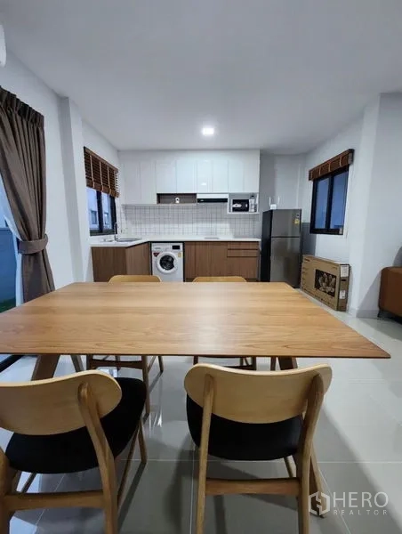 Townhouse for rent in Bang Phli, Samut Prakan - Dining area with a wooden table for four beside the bright modern kitchen.