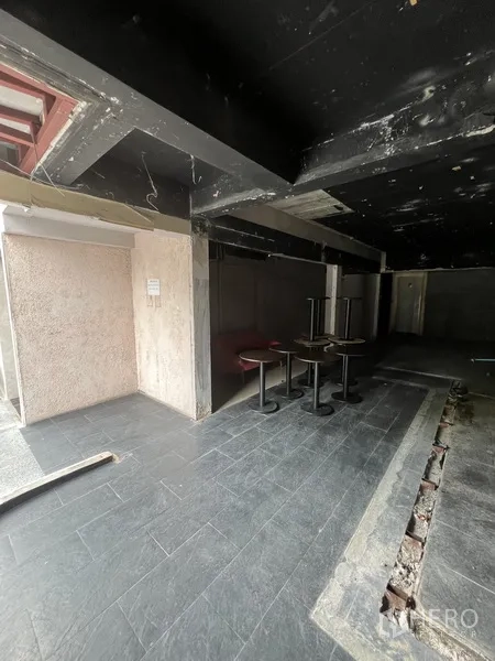 零售空间 出租在Watthana, Bangkok - 店面前部区域，地面铺砖、局部抬高平台与堆放的圆桌。