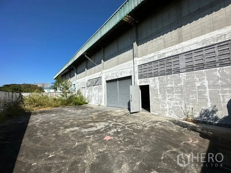 Factory for rent in Si Racha, Chon Buri - Rear service yard with roller shutter door, side personnel door and boundary wall.