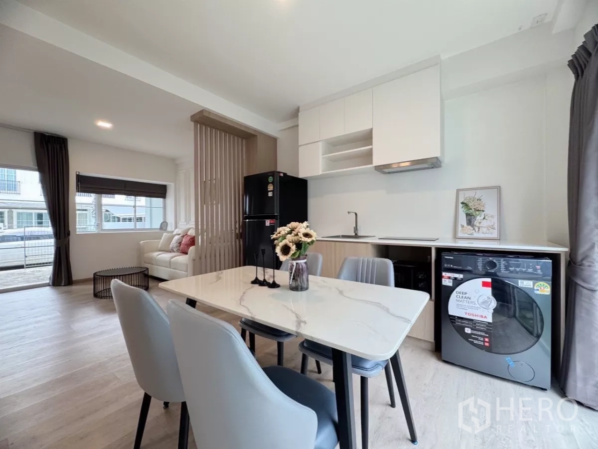 联排别墅 出租在Prawet, Bangkok - 厨房白色橱柜，岩板餐桌，冰箱与洗衣机。