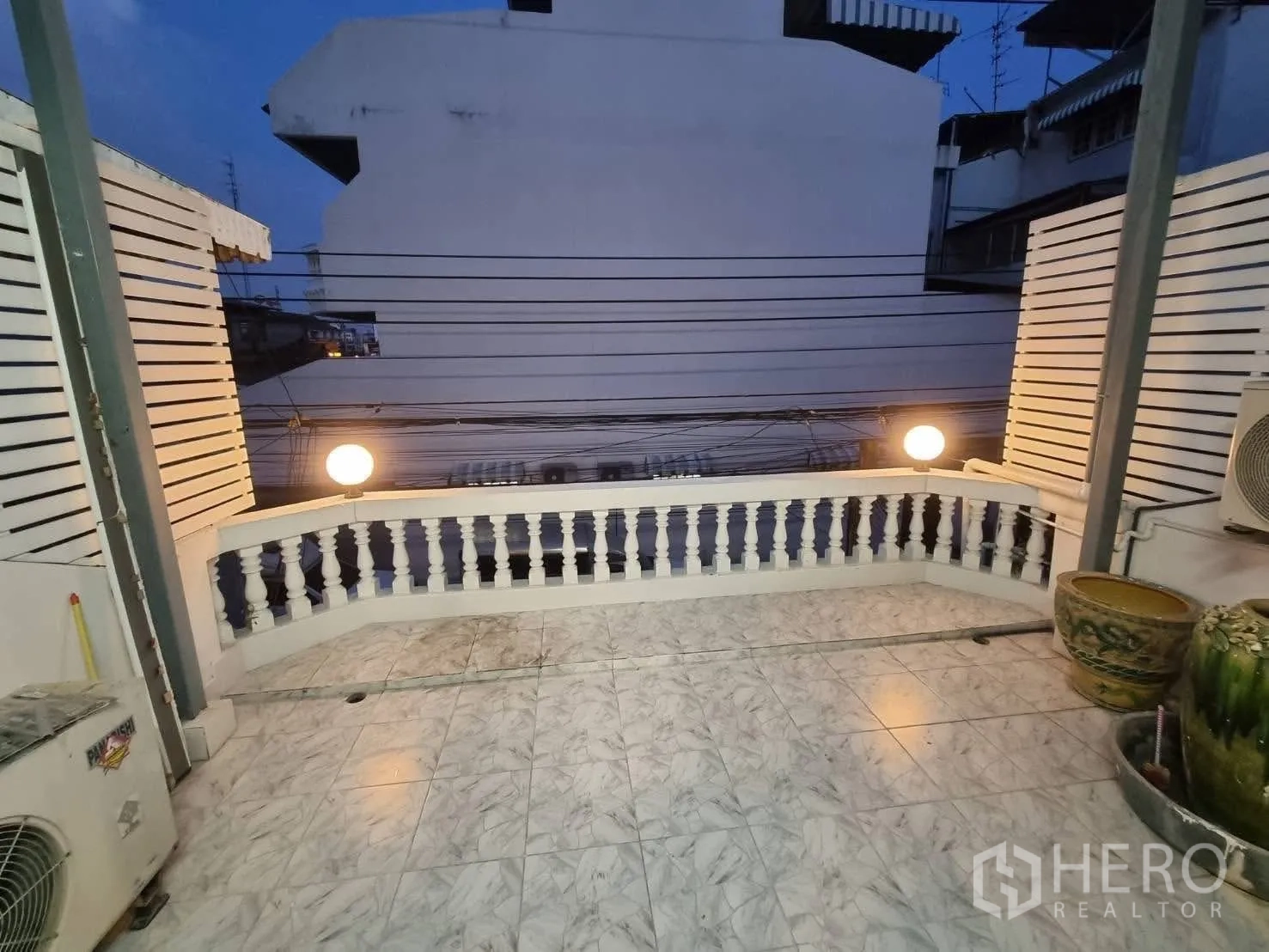 Townhouse for rent in Din Daeng, Bangkok - Upper terrace facing neighboring buildings with decorative railing and lights.