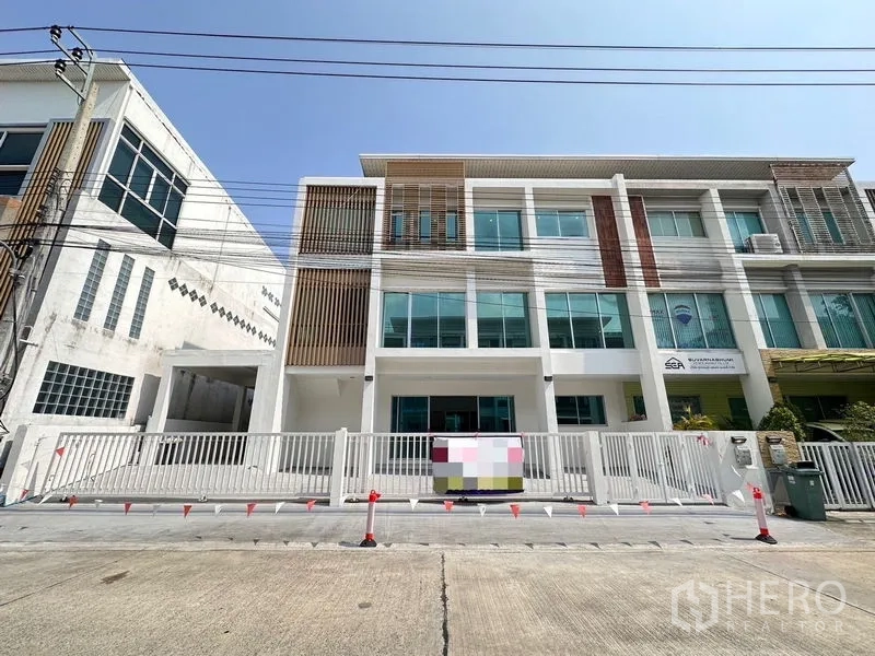 Home Office for sale in Lat Krabang, Bangkok - Front view of a modern three-storey home office with large glass windows, white facade and gated driveway.
