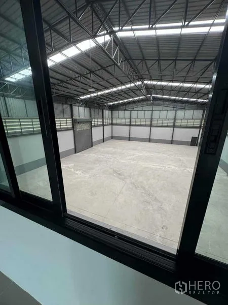 工厂 出售在Samut Sakhon - 从办公室窗户内看高跨仓库与钢结构屋顶。