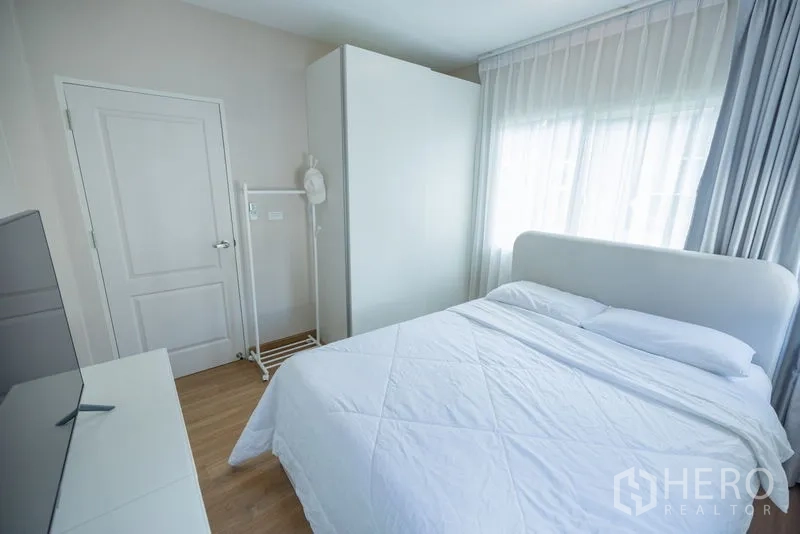 Detached House for rent or sale in Bang Phli, Samut Prakan - Cozy bedroom with white bed, wardrobe, TV and sheer drapes.