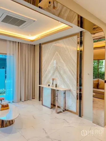 Detached House for sale in Bang Kapi, Bangkok - Lounge corner featuring a marble-vein feature wall, recessed lighting and a slim console table.