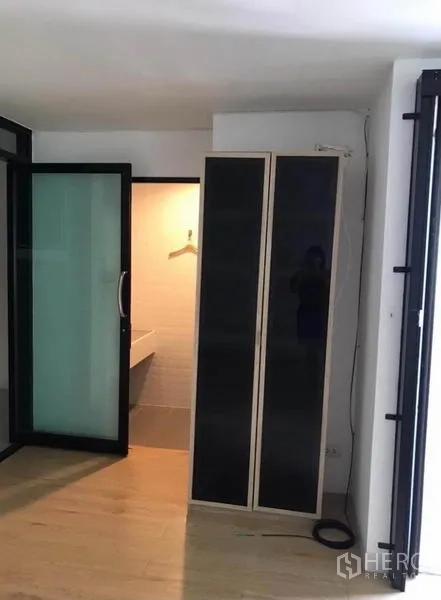 Townhouse for rent in Wang Thonglang, Bangkok - Bedroom corner with wardrobe and entry to bathroom through a frosted glass door.