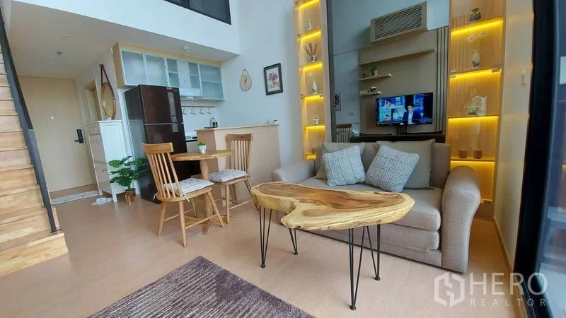 Condominium for rent in Watthana, Bangkok - Cozy living zone with sofa, live-edge wood coffee table and open kitchen with shelving.