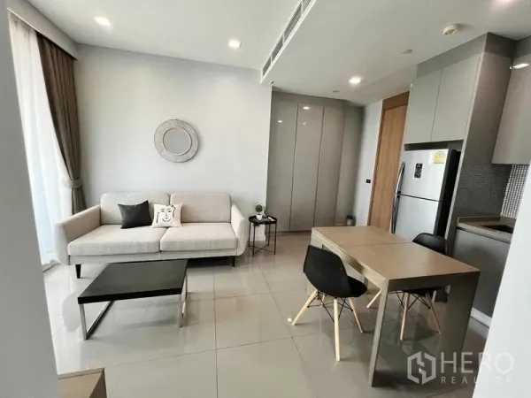 公寓 出租在Bang Rak, Bangkok - 明亮客厅，灰色沙发、餐桌与开放式厨房的现代公寓。