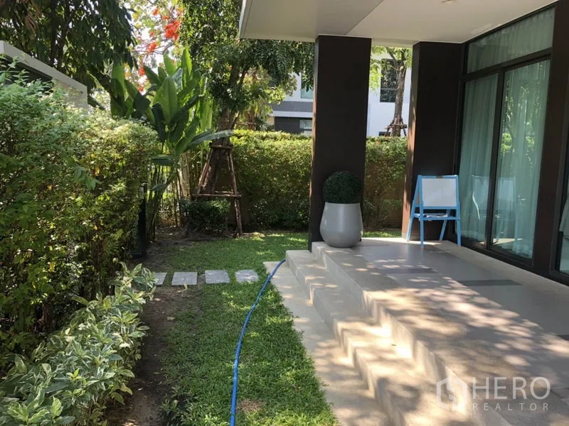 Detached House for rent or sale in Bang Kapi, Bangkok - Shaded garden terrace with steps, sliding glass doors and manicured hedges.