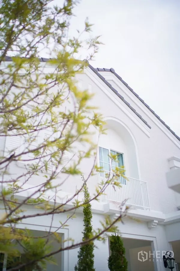Detached House for rent in Bang Phli, Samut Prakan - Modern white two-storey detached house facade with arched balcony and greenery.