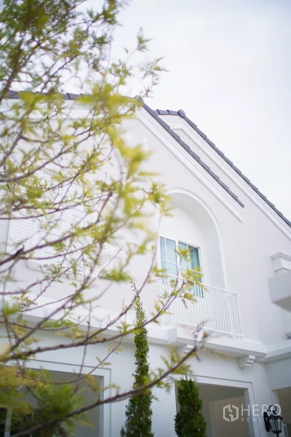 Detached House for rent in Bang Phli, Samut Prakan - Modern white two-storey detached house facade with arched balcony and greenery.
