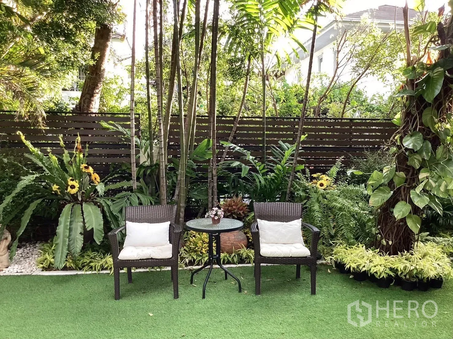 บ้านเดี่ยว for sale in Suan Luang, Bangkok - สวนร่มรื่นพร้อมเก้าอี้หวายสองตัวและโต๊ะกลมบนสนามหญ้า