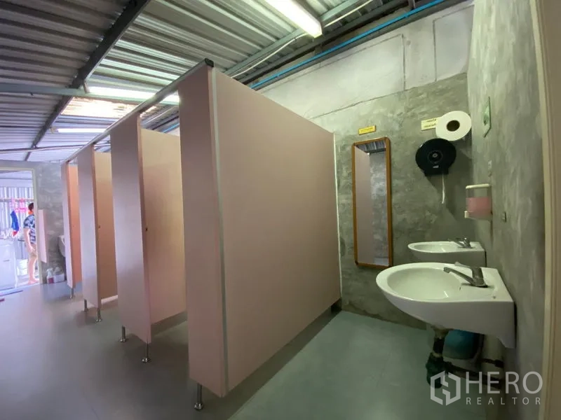 Warehouse for rent in Bueng Kum, Bangkok - Staff restroom with stalls and twin sinks inside the industrial facility.