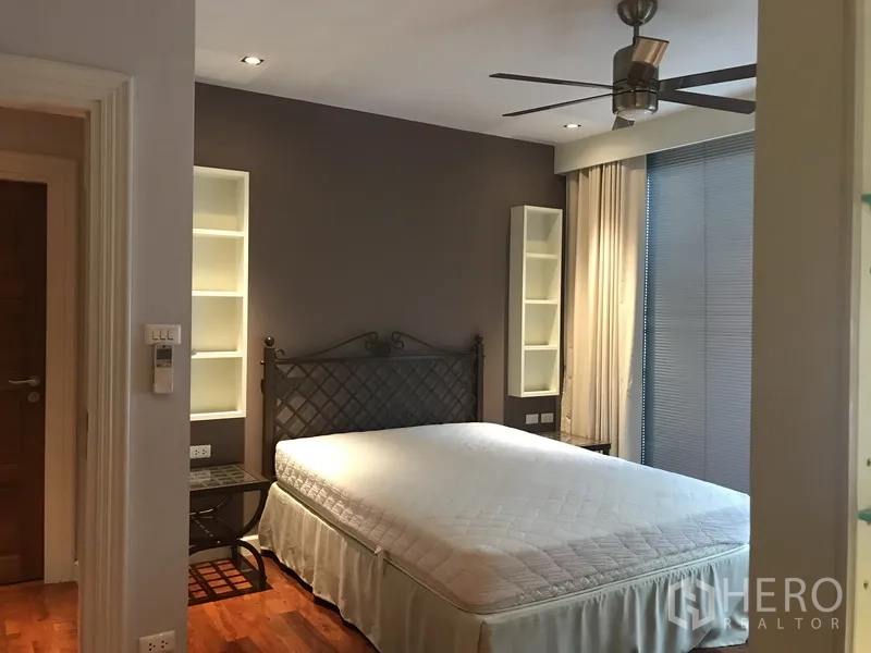 Apartment for rent in Pathum Wan, Bangkok - Cozy bedroom with ceiling fan, bedside display shelving and soft natural light.