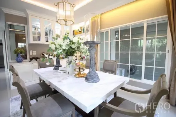 บ้าน ให้เช่าหรือขายในLat Phrao, Bangkok - มุมใกล้ของส่วนรับประทานอาหาร โต๊ะหินอ่อนสีขาว เก้าอี้พนักพิงสูง และผนังกระจกเต็มบาน