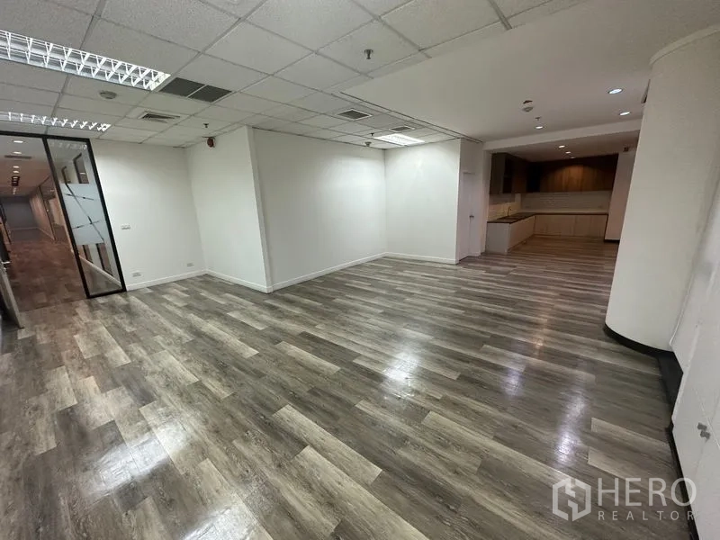 Office Space for rent - Open work area leading to a fitted pantry, suspended ceiling lighting and wide wood-look floors.