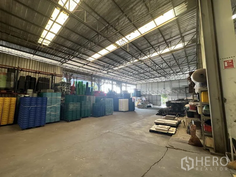 Factory for rent or sale in Khlong Luang, Pathum Thani - Alternative view of the ventilated warehouse showing skylights and inventory.