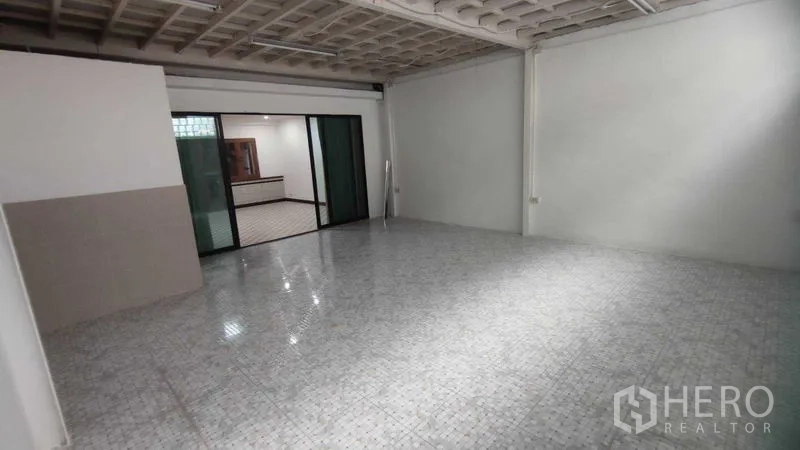 Home Office for rent in Watthana, Bangkok - Large multipurpose tiled room with exposed ceiling and sliding glass partition.