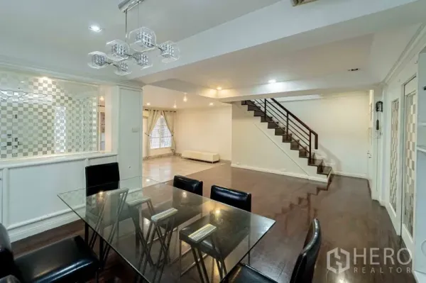 สำนักงานที่บ้าน ให้เช่าในBang Rak, Bangkok - โถงนั่งเล่นและรับประทานอาหารแบบโอเพ่น พร้อมโต๊ะกระจก โคมไฟสมัยใหม่ และพื้นไม้ต่อเนื่องสู่บันได