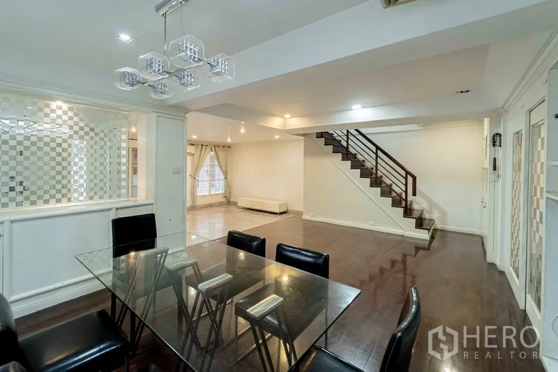 สำนักงานที่บ้าน ให้เช่าในBang Rak, Bangkok - โถงนั่งเล่นและรับประทานอาหารแบบโอเพ่น พร้อมโต๊ะกระจก โคมไฟสมัยใหม่ และพื้นไม้ต่อเนื่องสู่บันได