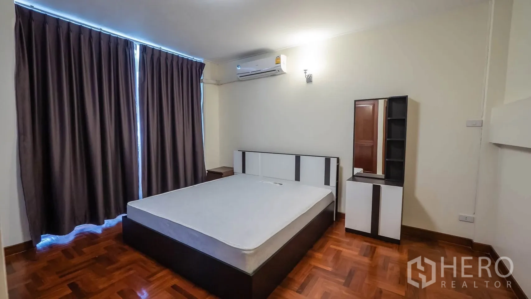 Townhouse for rent in Watthana, Bangkok - Bedroom with queen bed, dresser, air conditioning, and blackout curtains.