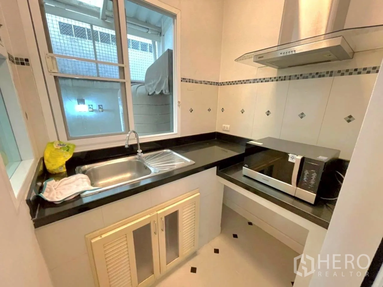 联排别墅 for rent in Bang Kho Laem, Bangkok - 紧凑厨房配黑色台面、不锈钢水槽、抽油烟机与微波炉。