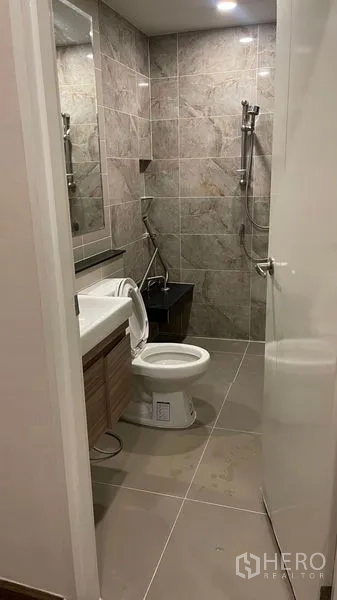 Detached House for rent or sale in Prawet, Bangkok - Contemporary bathroom with tiled walls, vanity, toilet and handheld shower.