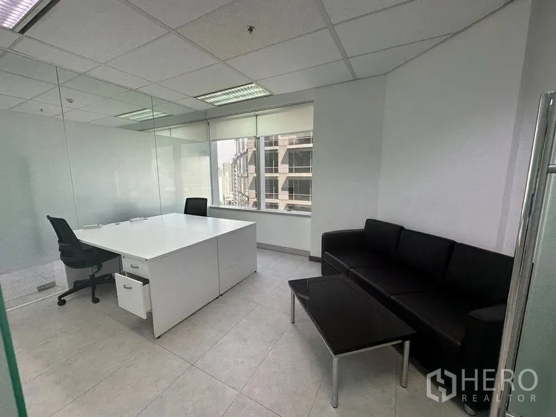 Office Space for rent - Private office with glass partitions, black sofa and white executive desk.