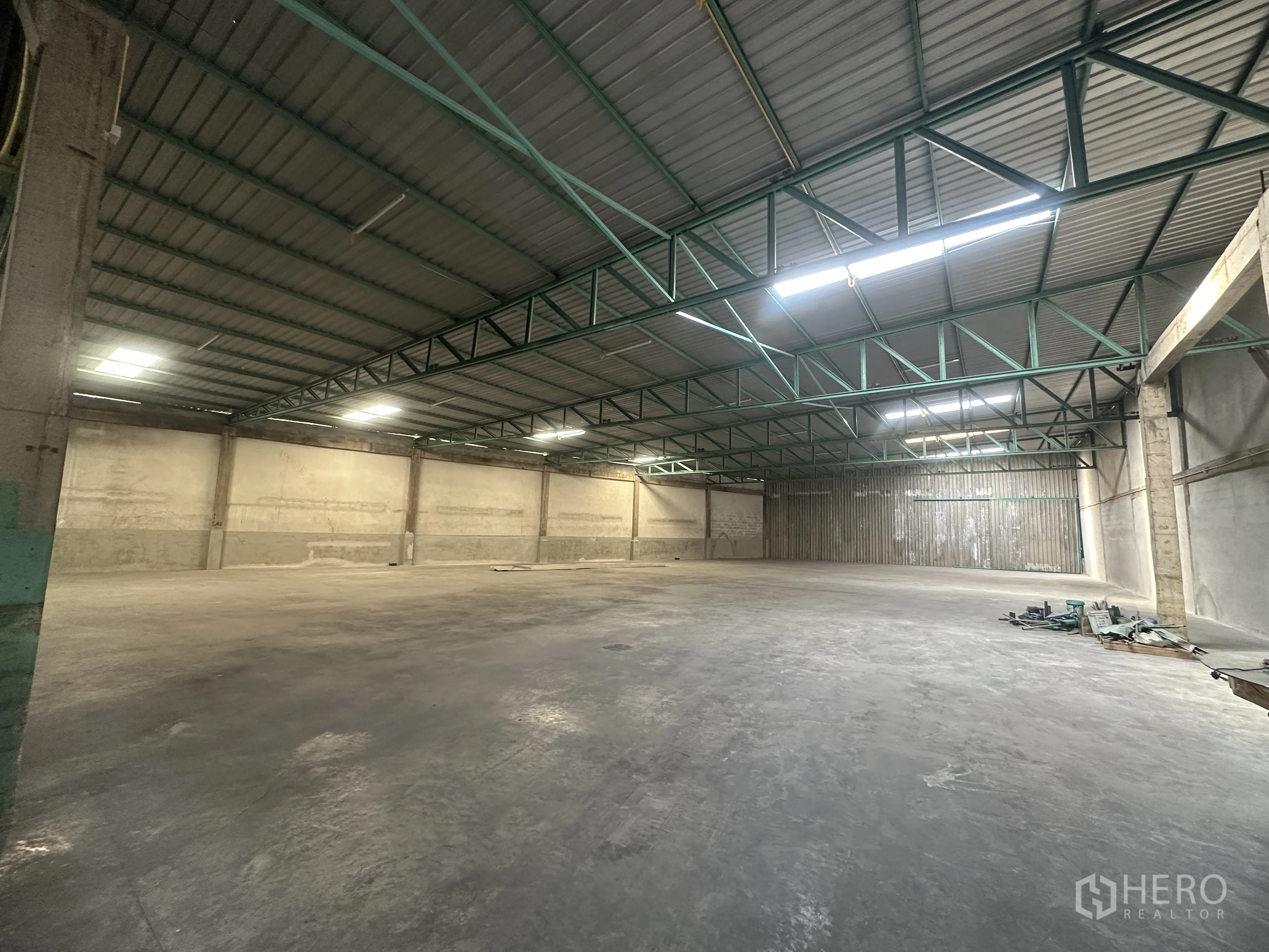 货栈 出租在Mueang Pathum Thani, Pathum Thani - 仓库内部宽敞，高钢桁架屋顶、平整混凝土地面与长条照明。