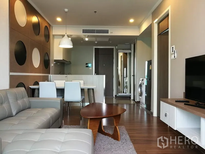 Condominium for rent in Sathon, Bangkok - Open-plan living and dining area with modern kitchenette, four-seat dining table and wood floors in a Bangkok condo.