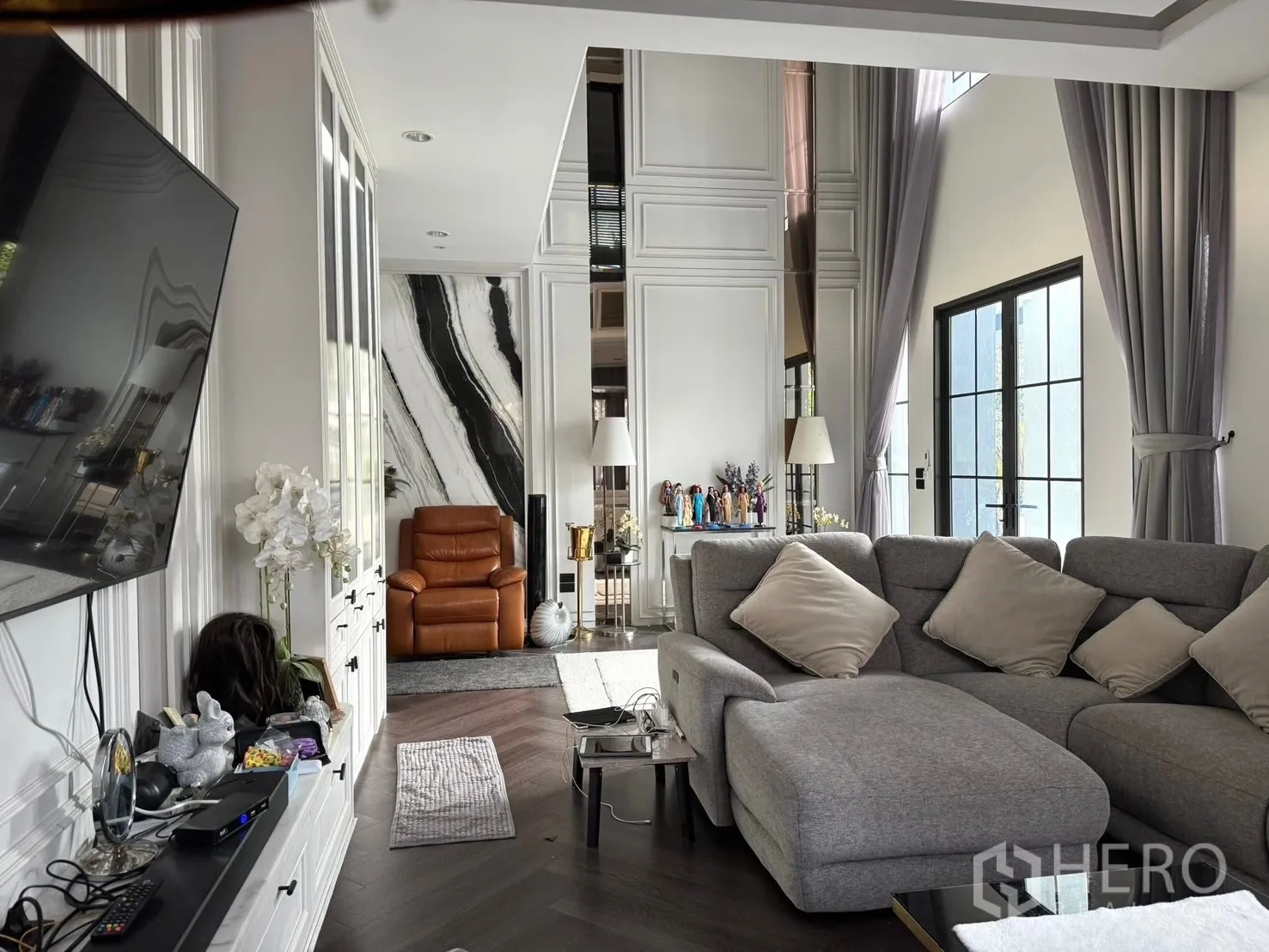 独立式住宅 出售在Mueang Pathum Thani, Pathum Thani - 家庭客厅，灰色转角沙发、护墙板与自然采光。