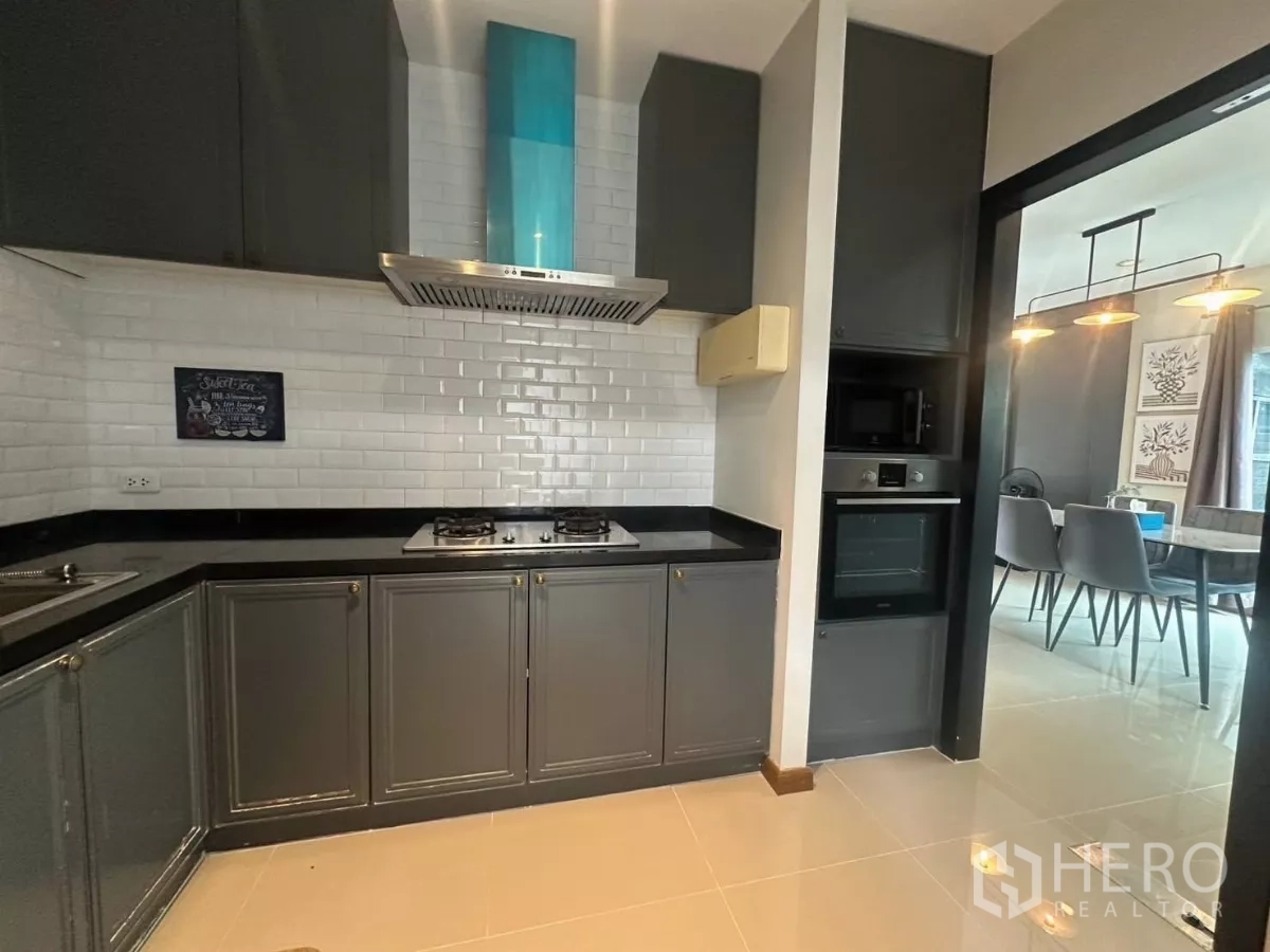 บ้าน ให้เช่าในSuan Luang, Bangkok - ครัวตกแต่งผนังกระเบื้องซับเวย์สีขาว เตาแก๊ส เครื่องดูดควัน และเตาอบบิวท์อิน.