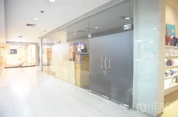 Office Space for rent in Khlong Toei, Bangkok - Glass-front office unit with double doors along a bright indoor corridor in Phra Khanong.