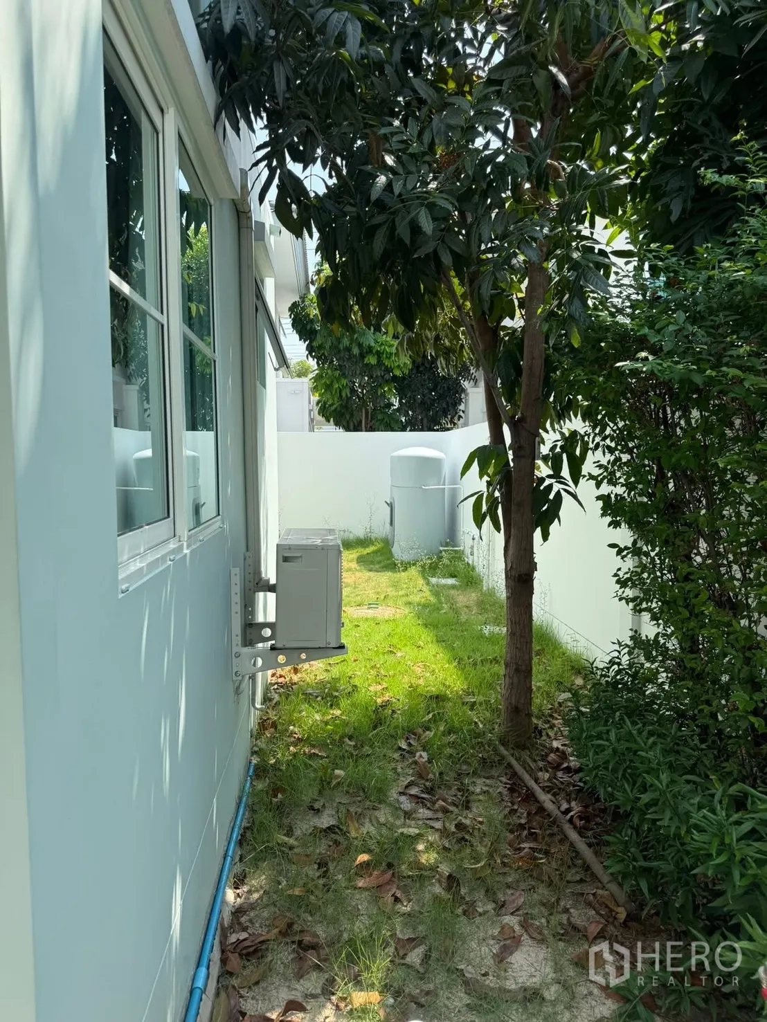 独栋房屋 for rent in Bang Phli, Samut Prakan - 房屋侧边的小花园，草地、乔木和外挂机沿墙排列。