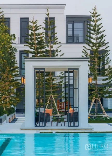 独立式住宅 出售在Saphan Sung, Bangkok - 泳池畔白色凉亭，设有座位，周围种植高大松树。