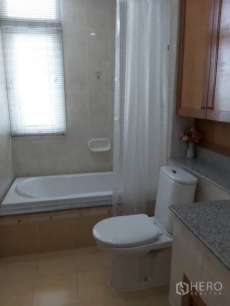 公寓 出租在Watthana, Bangkok - 浴室设浴缸、浴帘、坐便器与窗下花岗岩台面。