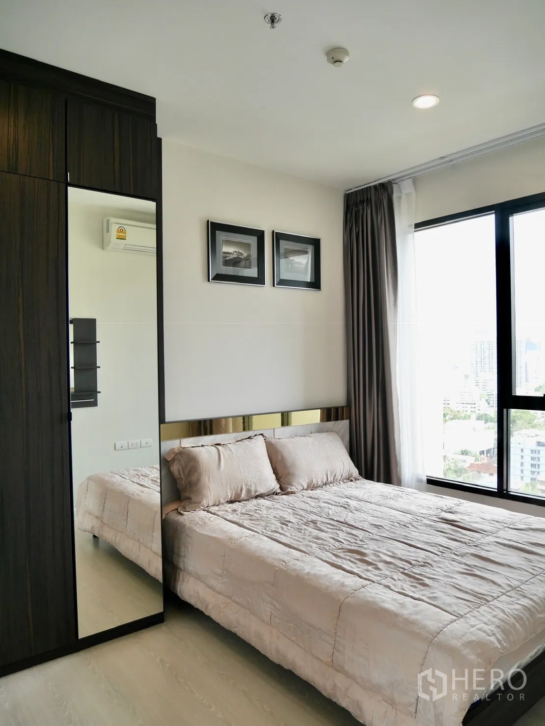 Condominium for rent in Pathum Wan, Bangkok - Cozy bedroom with large window, built-in wardrobe and neutral bedding.
