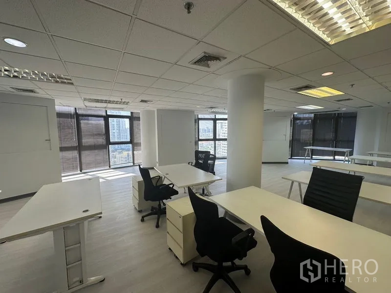 办公空间 出租 - 转角工作区，工位与椅子，环景窗户带城市景观。